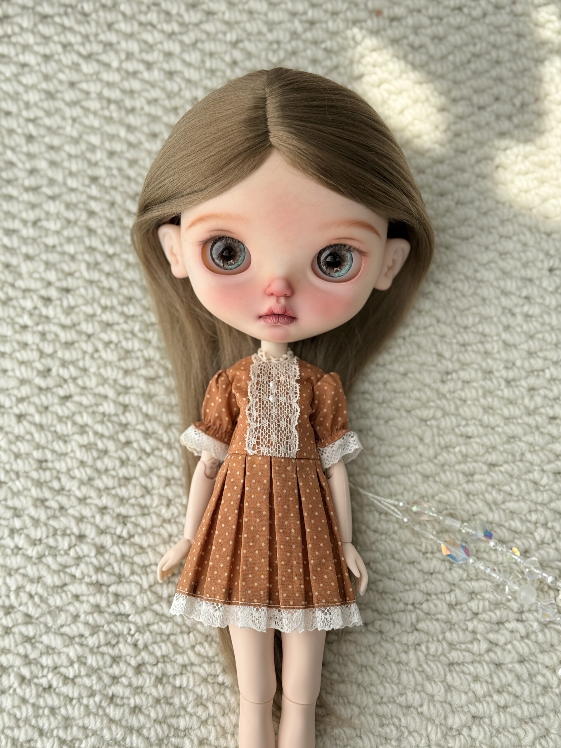 Doll wearing the Pumpkin Lace Vintage Dress with a lace front, polka dots, and a pleated skirt.