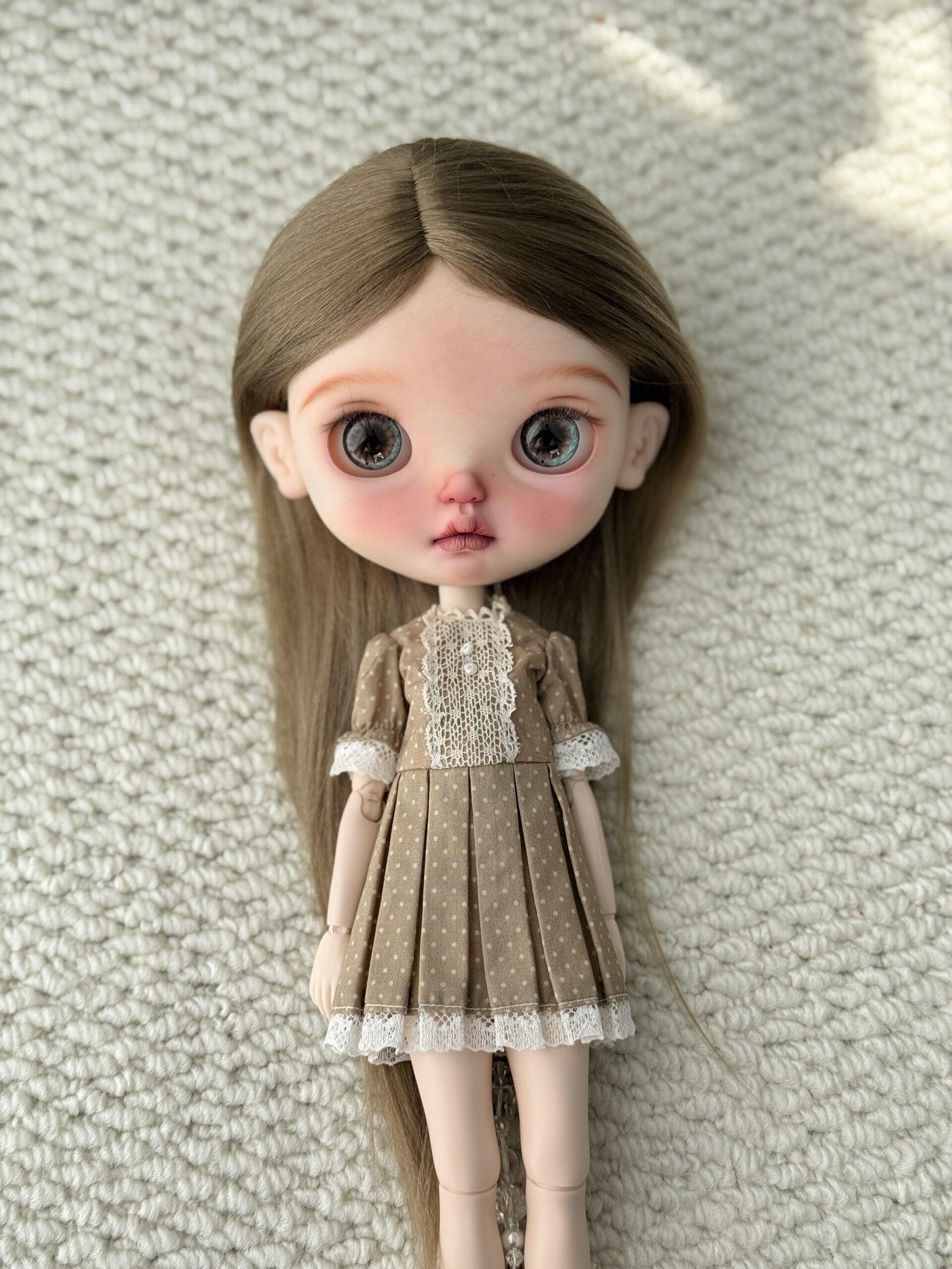 Doll wearing the Khaki Brown Lace Vintage Dress with a lace front, polka dots, and a pleated skirt.